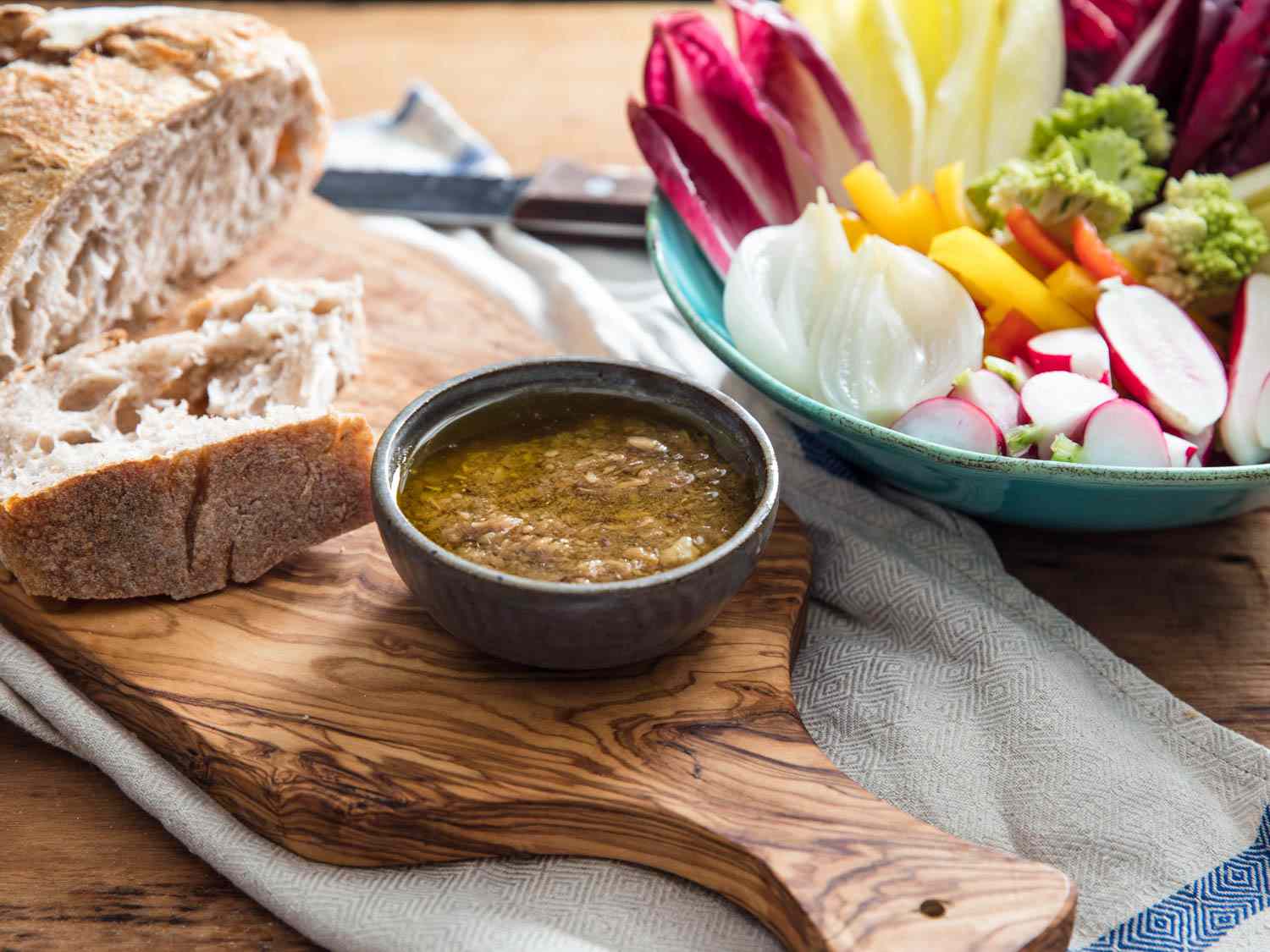 A bowl of bagna càuda, served with bread and a platter of vegetables. 