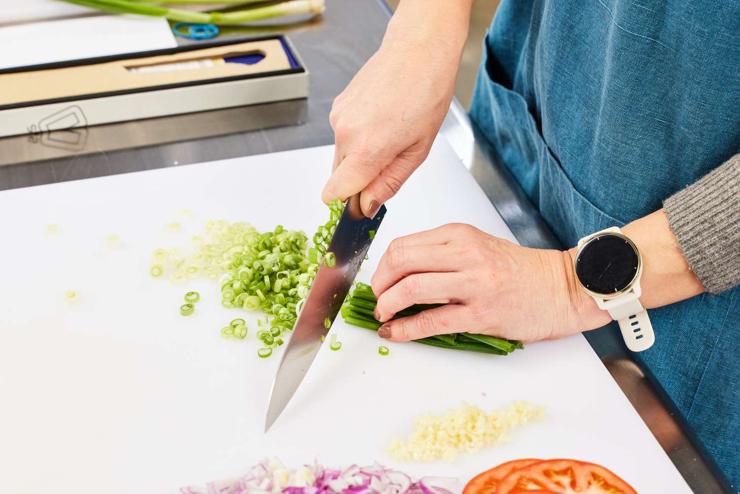 Hands slicing scallions with a Misono UX10 8.2-Inch Gyutou