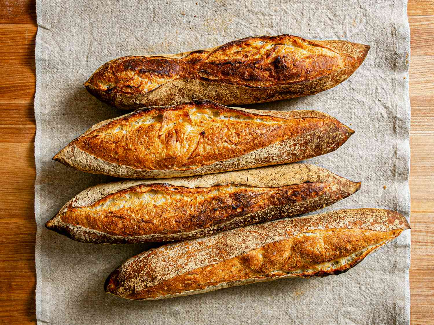 Overhead view of 4 baguettes on a grey table runner