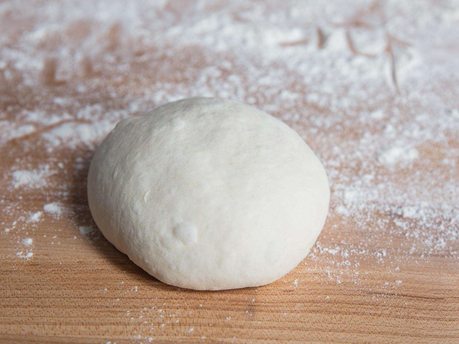 a ball of pizza dough on a floured work surface