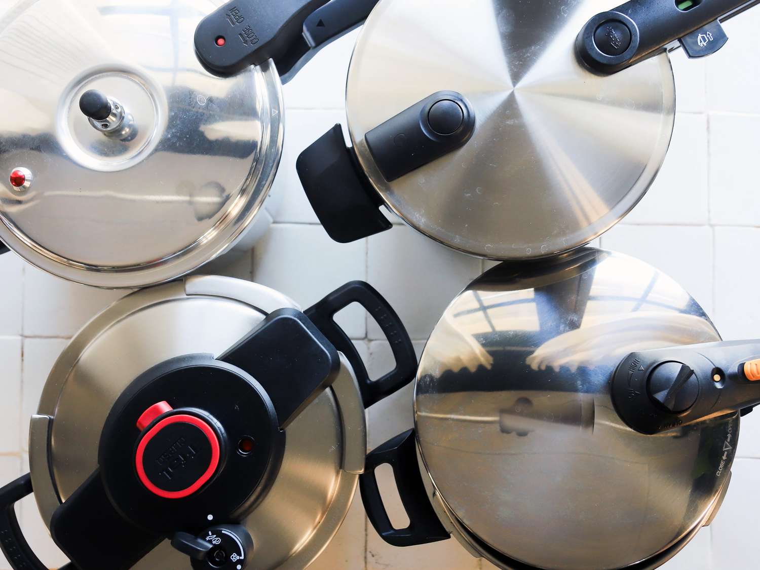 Four pressure cookers displayed on a tile surface