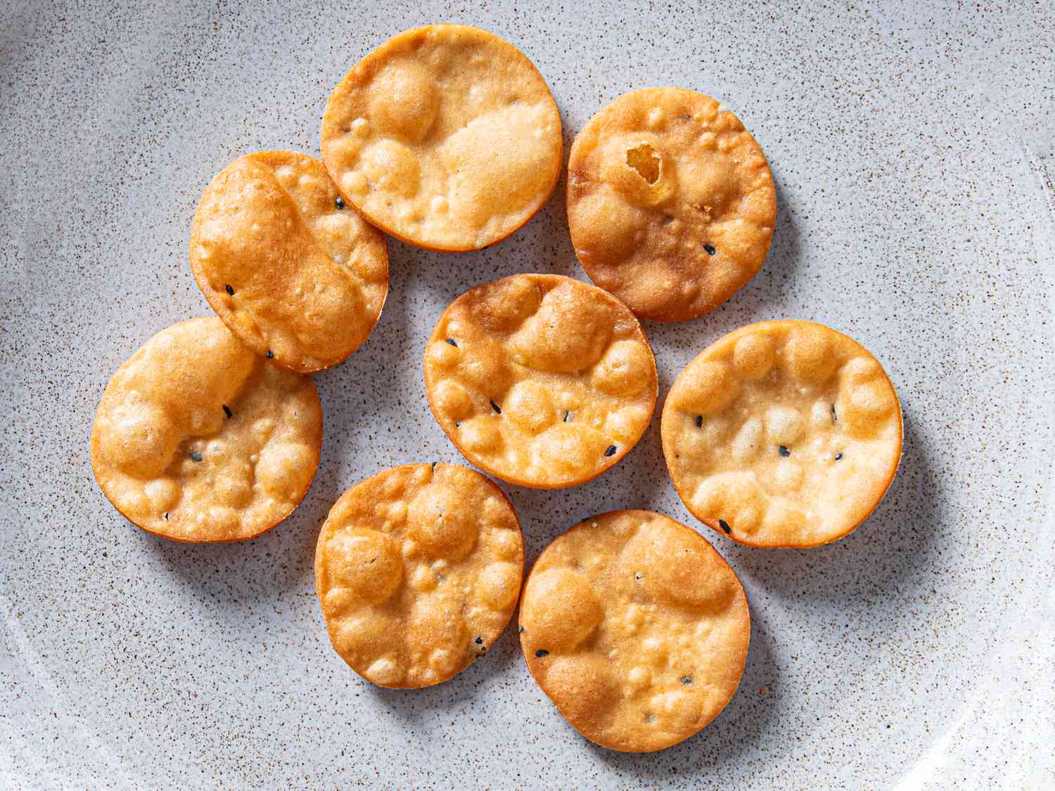 Golden brown chaat crisps resting on a ceramic plate.