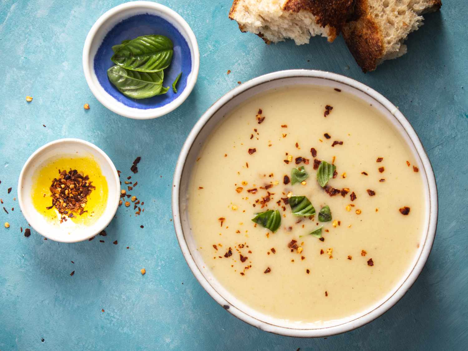 roasted garlic and parmesan soup in a bowl with red pepper flakes and basil as garnish