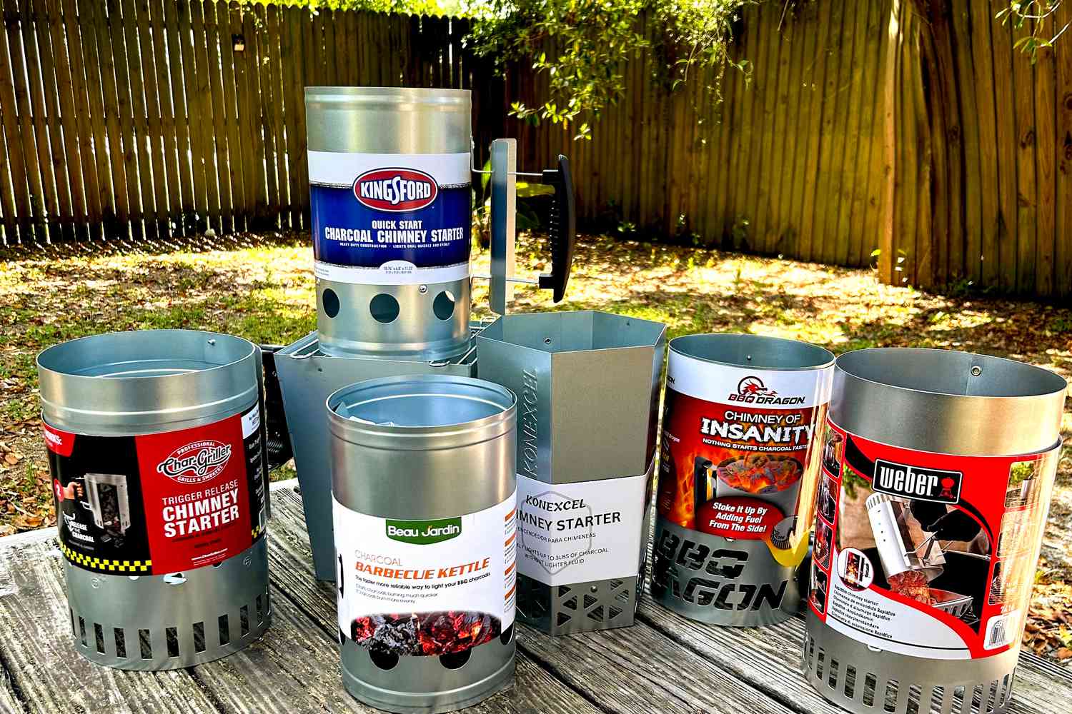 a variety of charcoal chimneys on a wooden picnic table 