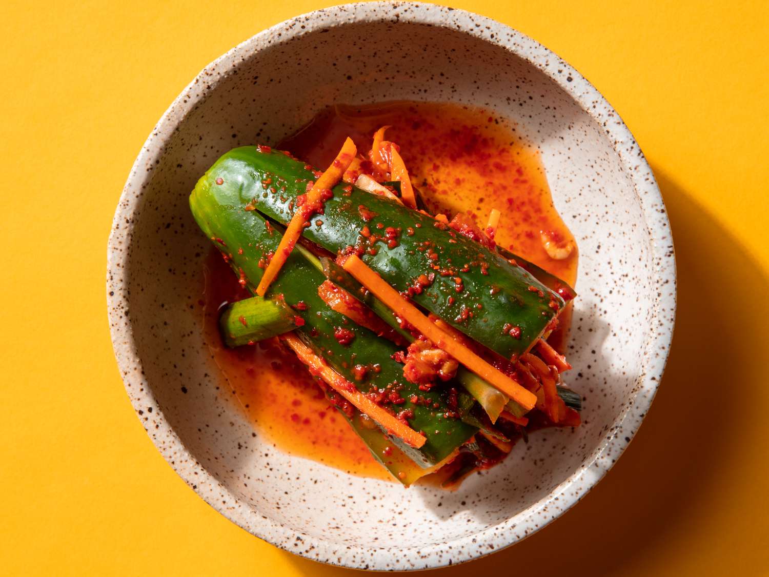 Overhead of a piece of stuffed cucumber kimchi in a small serving bowl.