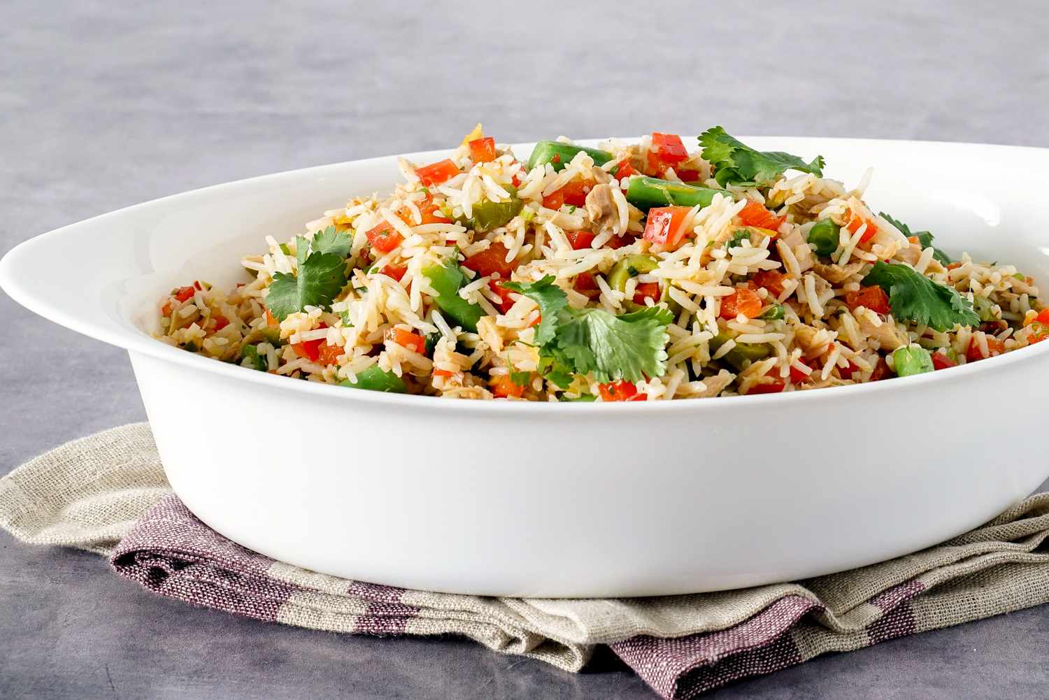 A white dish holding North African tuna and rice salad. The dish is sitting on a folded towel.