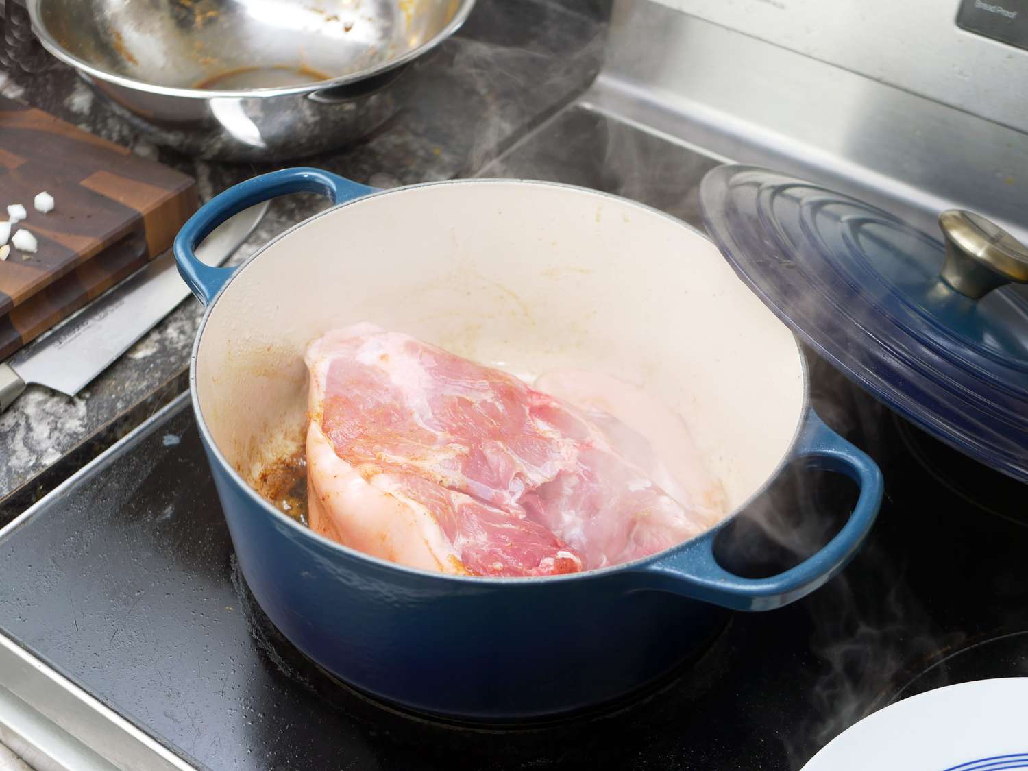 the le creuset dutch oven with a piece of pork shoulder searing in it. 