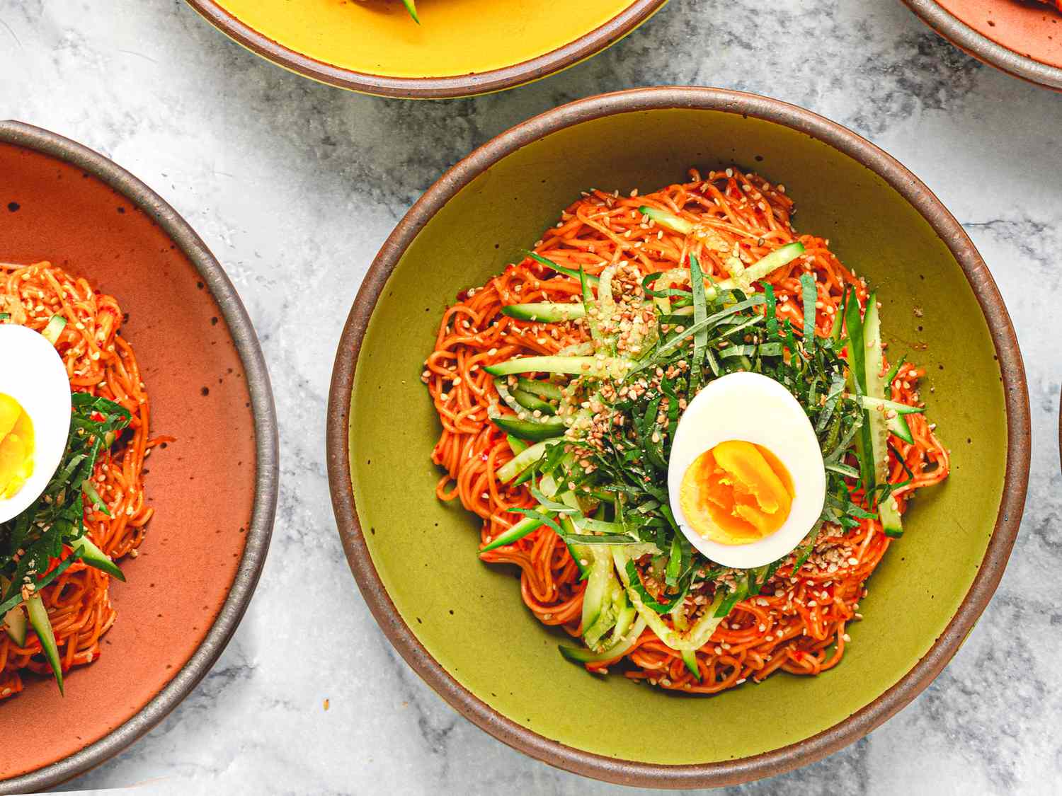 Bowls of Bibim Guksu topped with half a jammy egg