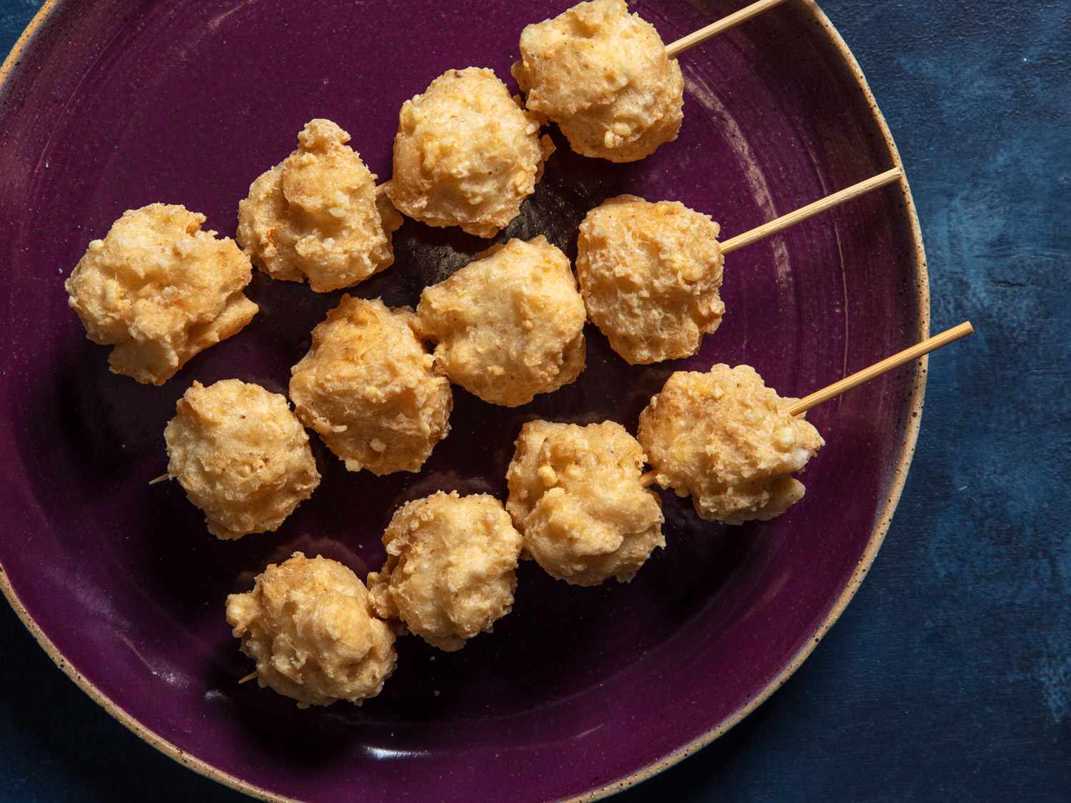 Three wood skewers with 4 squid balls each on a plate.