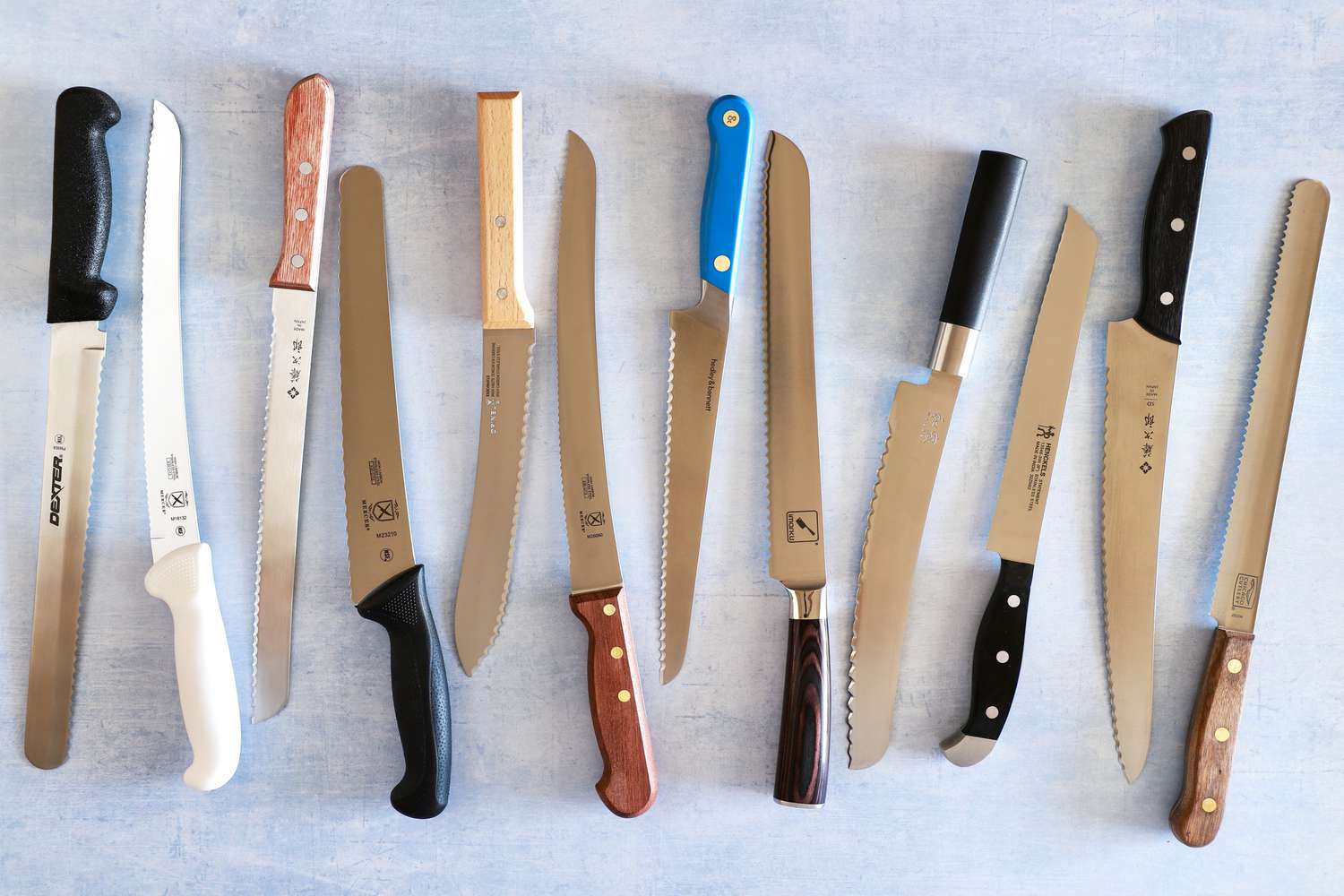 Group of serrated bread knives displayed on a blue surface