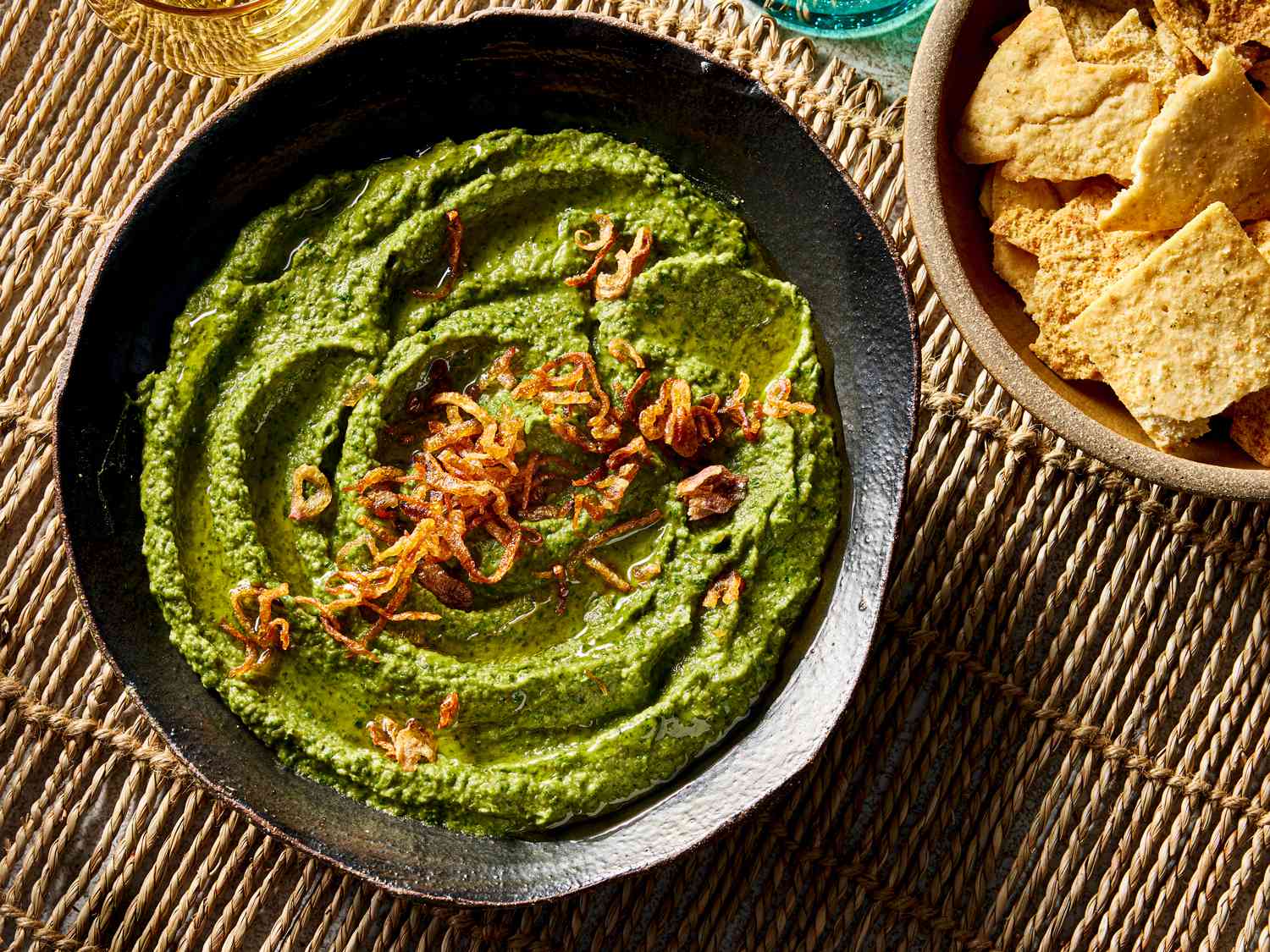 Overhead view of Egyptian bissara, served in a black ceramic bowl with crispy flatbreads.