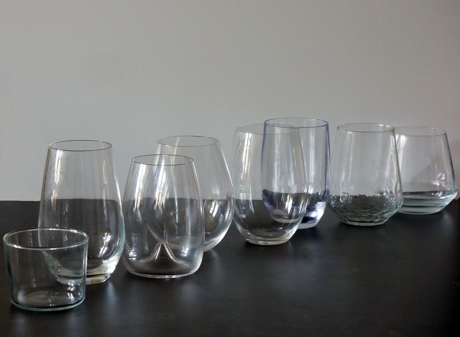 the lineup of wine glasses tested on a black countertop with white background