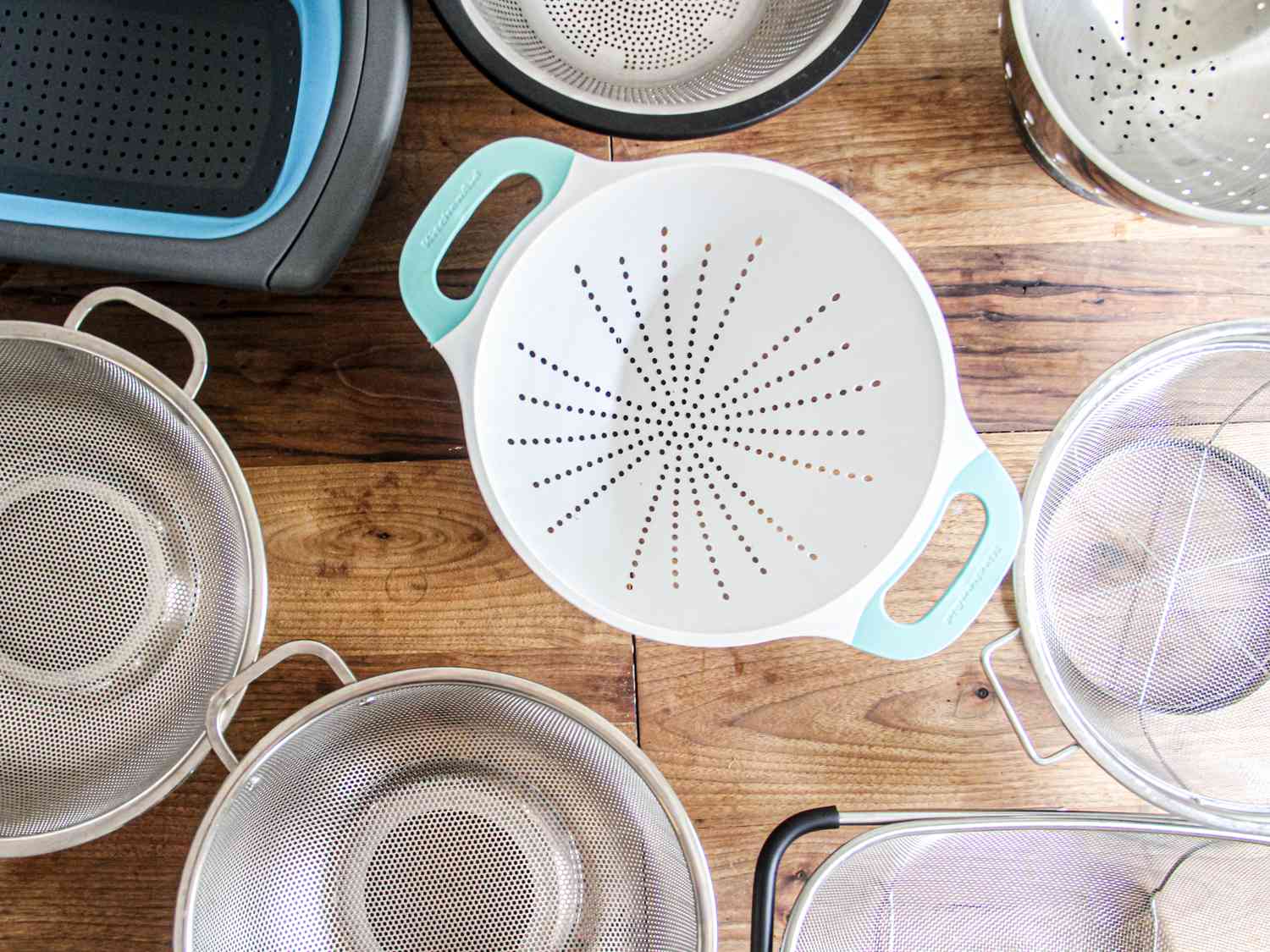 an overhead shot of a number of colanders on a wooden surface