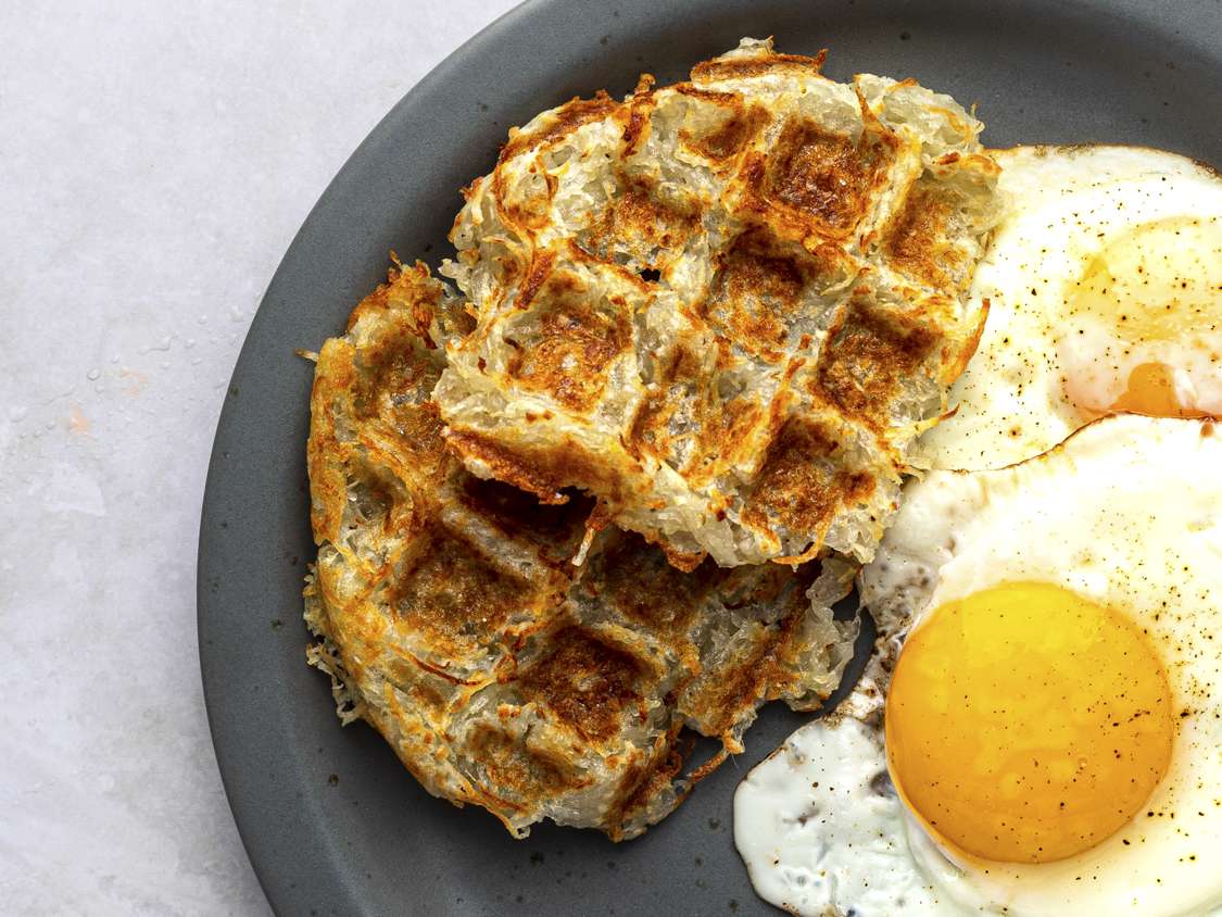 Waffle-iron hash browns on a plate with sunny side up eggs.