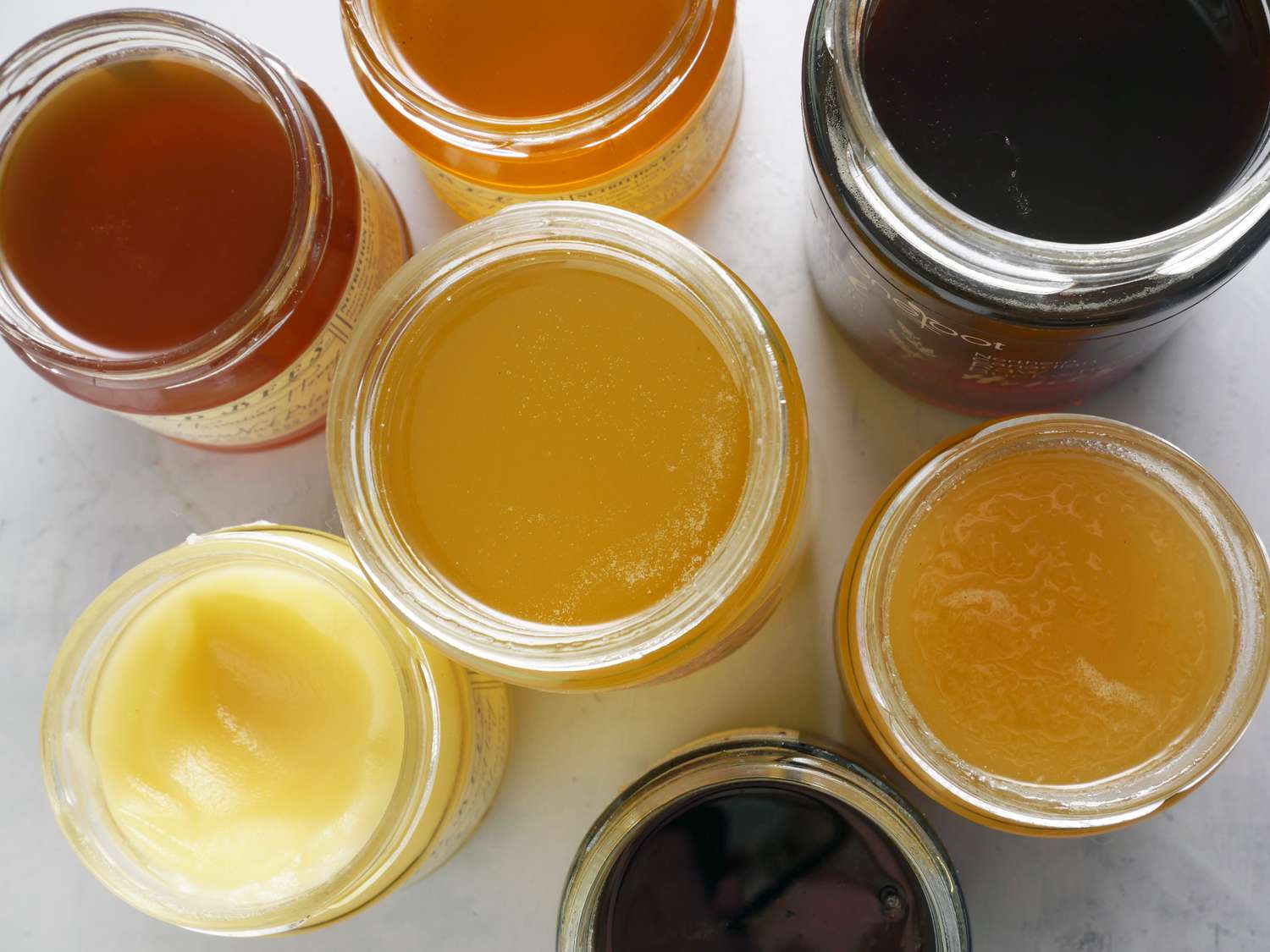 a variety of jars of honey with their tops open