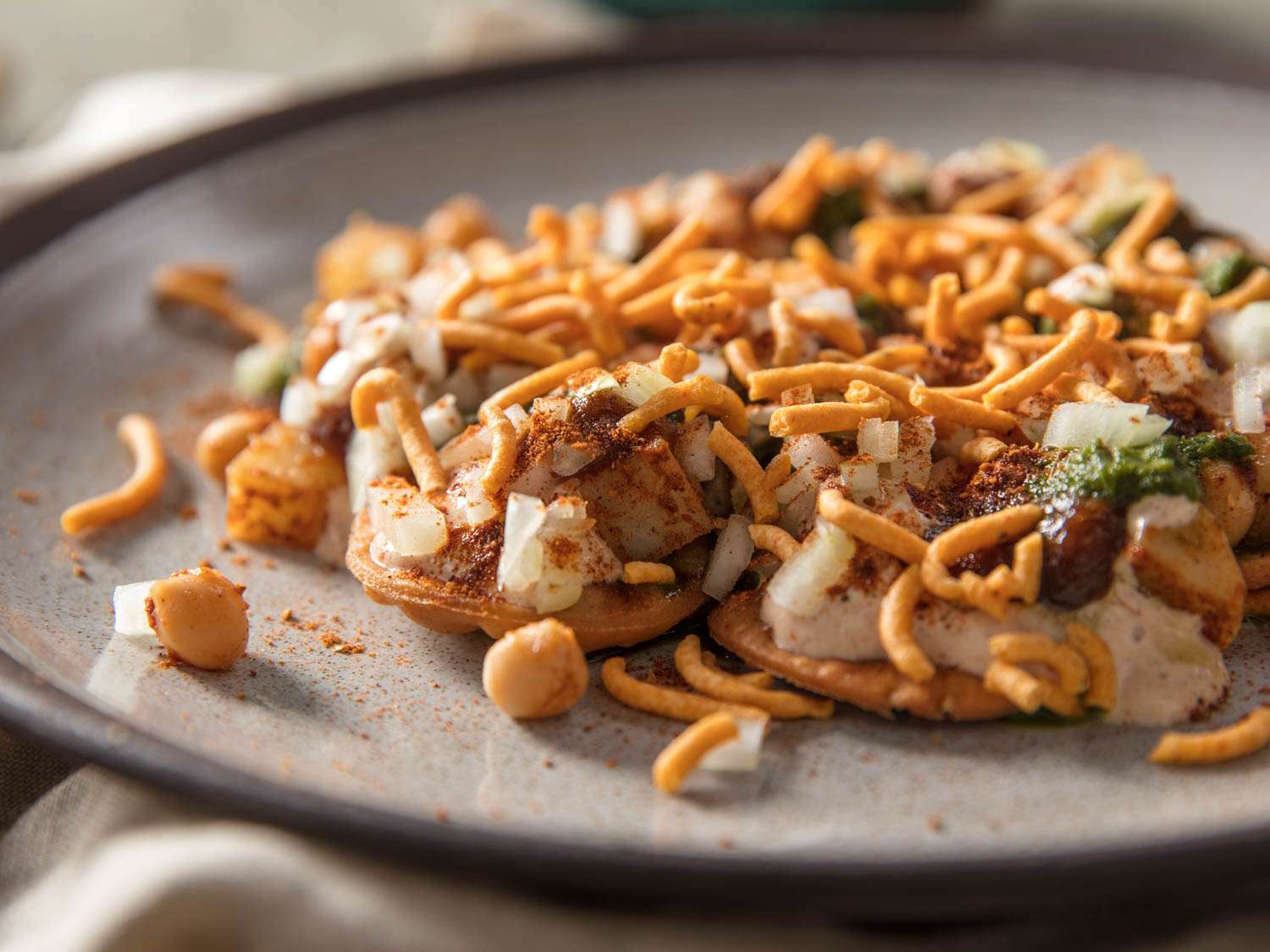 A plate of composed papri chaat (a type of Indian street food made of multiple components) highlighting the sev topping.