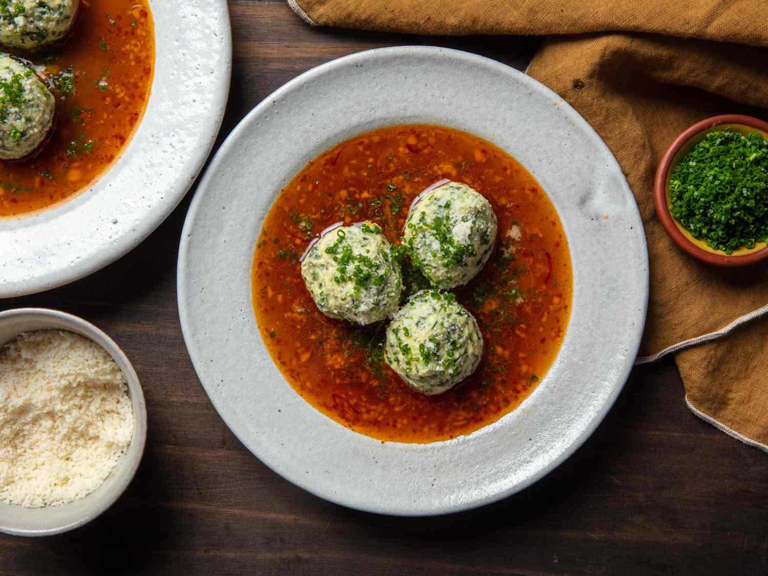 gnudi in a bowl with chives and parmesan cheese on the side