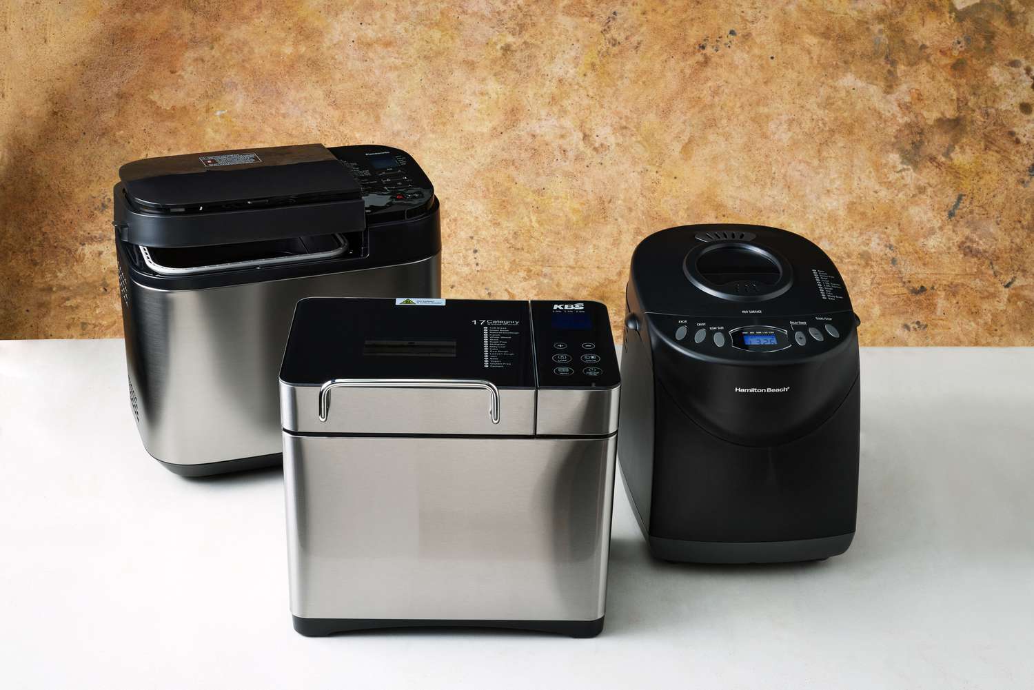 Three bread machines lined up on a counter 