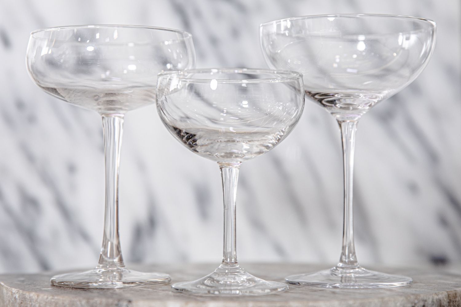 Three coupe glasses of varying sizes against a white background