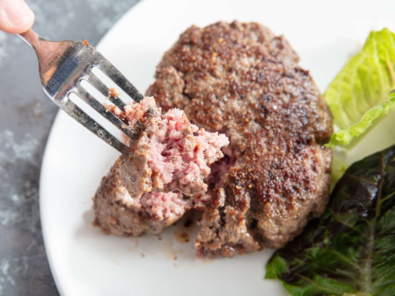 Hache Steak with a bite on a fork on a white plate 