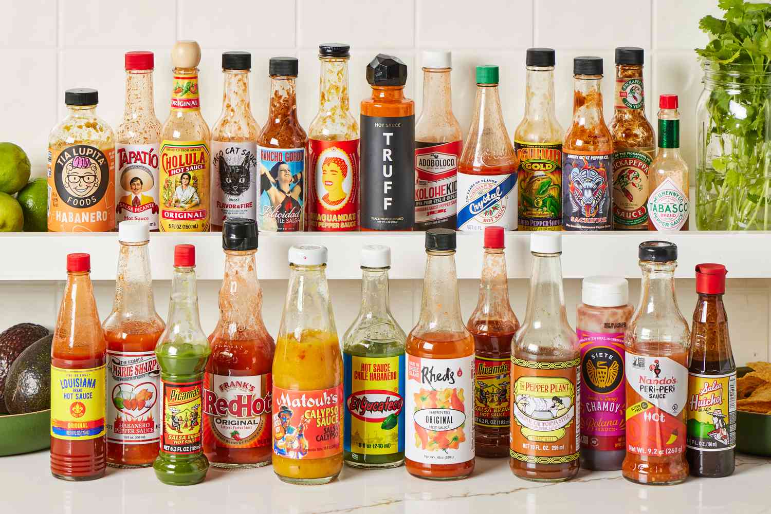 Numerous bottles of hot sauces on a kitchen countertop.