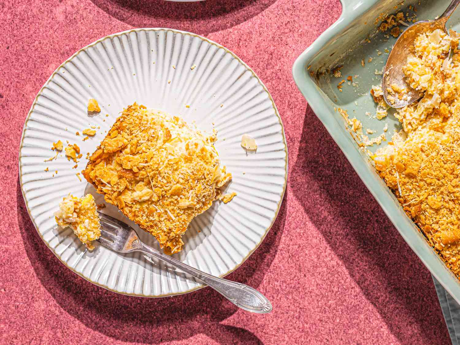 Overhead view of a square of yellow squash casserole on a small ridged plate.