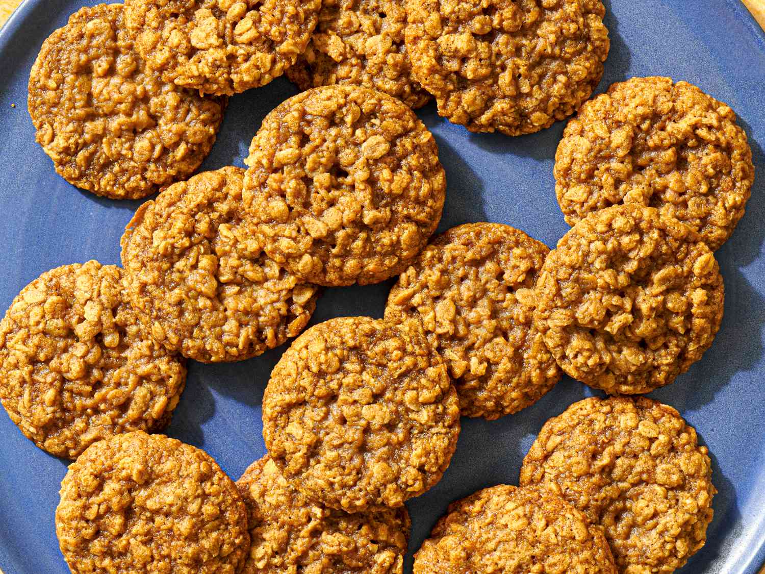 A blue ceramic plate holding many maple brown sugar oatmeal cookies.