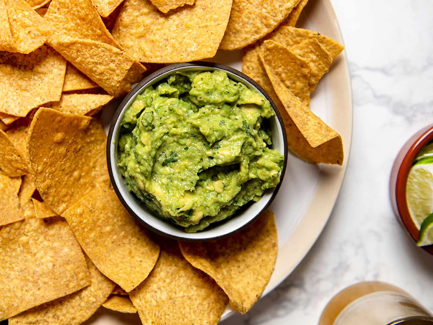 Bowl of guacamole set inside a platter of tortilla chips