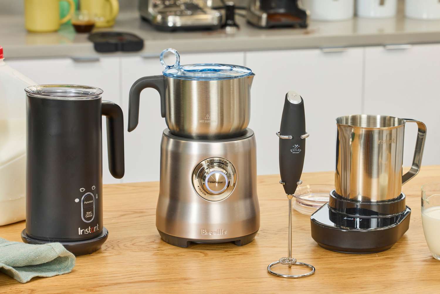 Four milk frothers on a kitchen countertop.