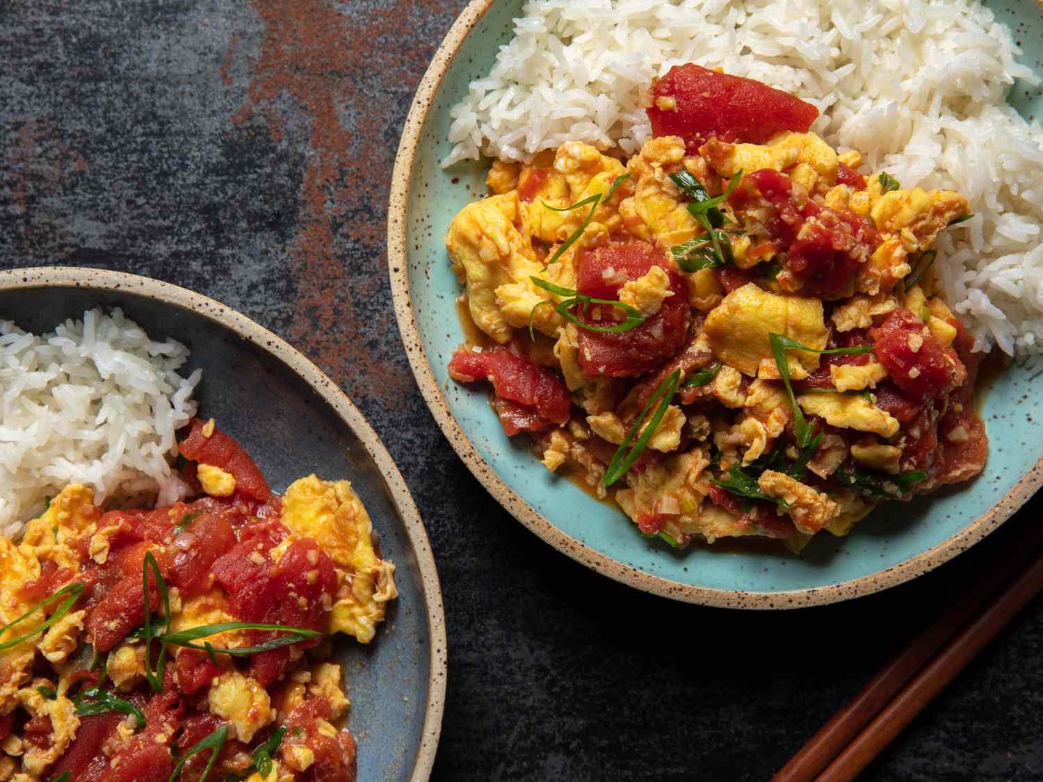 Two plated dishes of tomato and egg with rice.