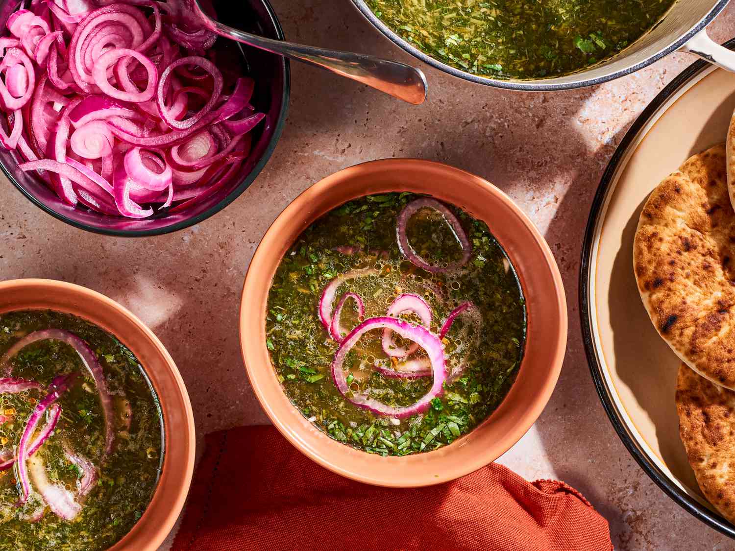 Molokhia soup in a bowl with pickled red onions.