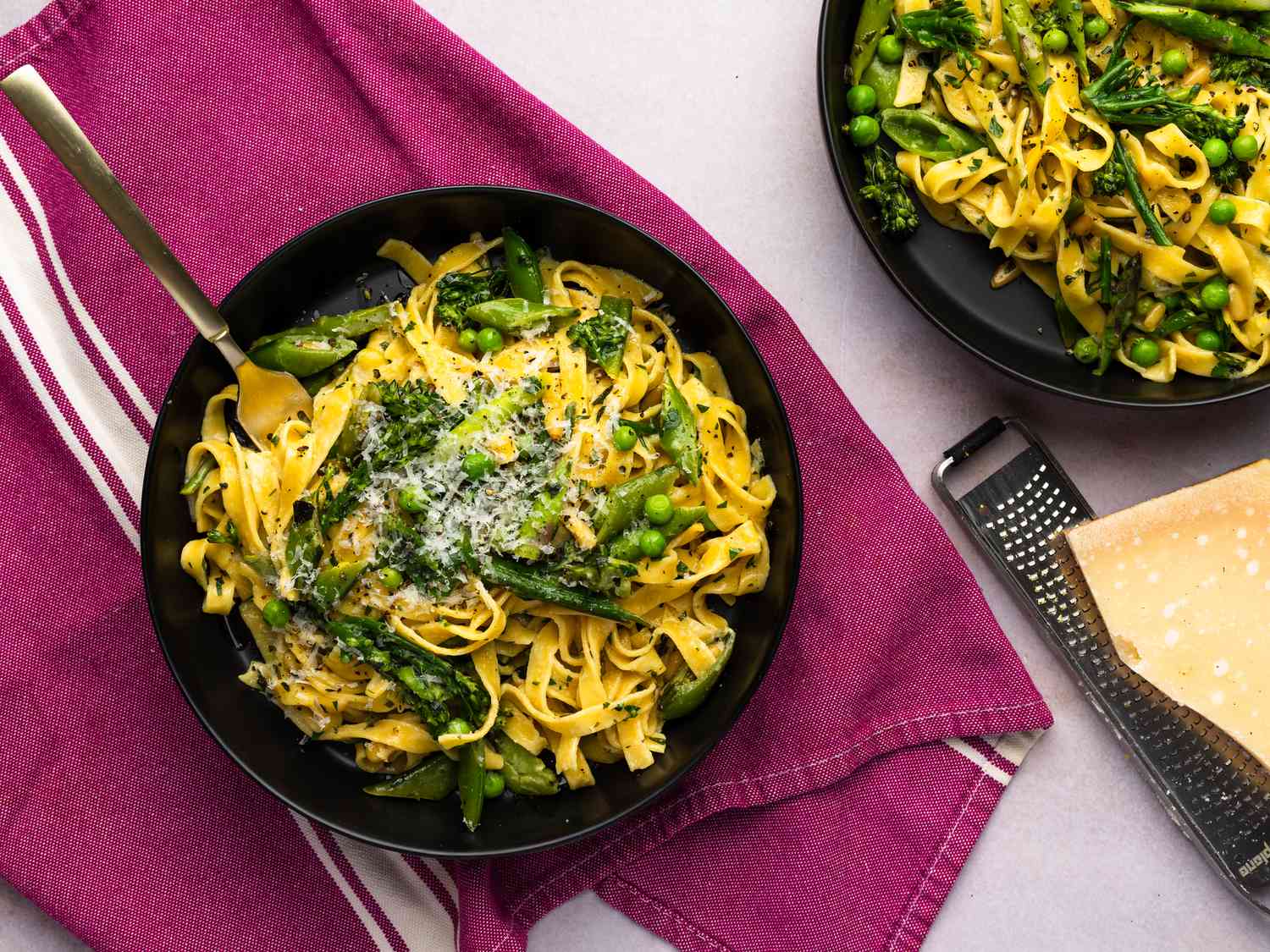 Pasta Primavera served inside a dish, drizzled with olive oil, sprinkled with freshly ground black pepper, and served with grated Parmigiano-Reggiano 