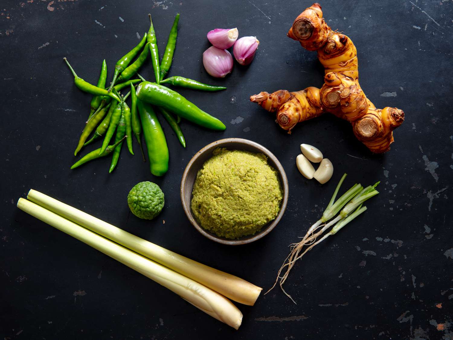 green curry paste in a small bowl with prominent ingredients surrounding it