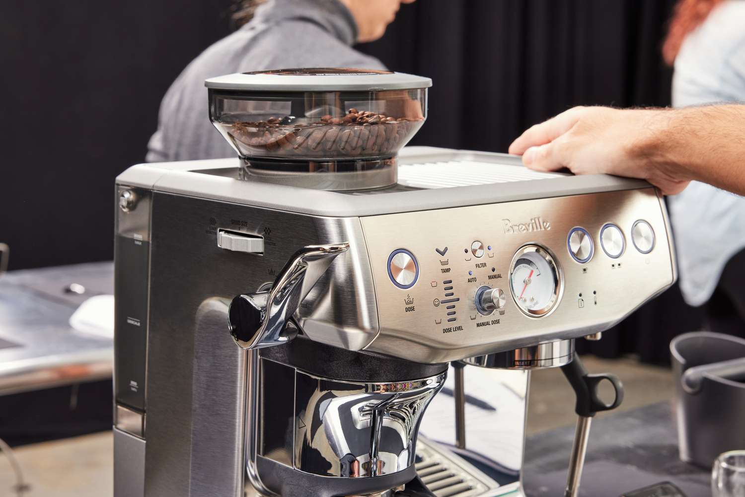 A person holding one side of the Breville Barista Express Impress