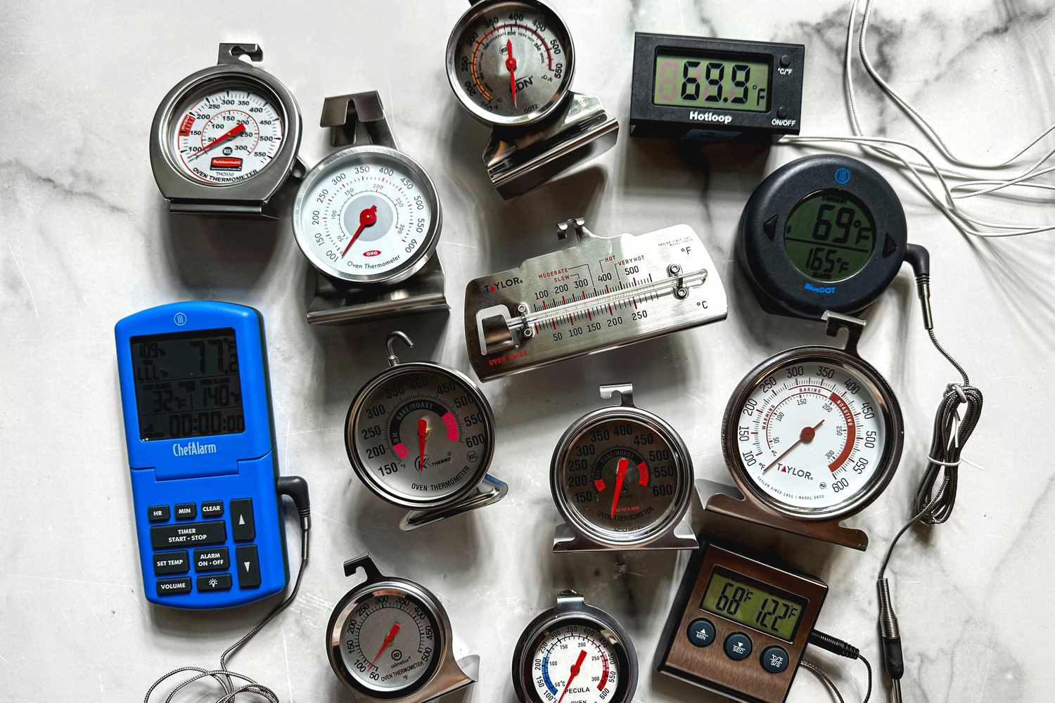 A collection of oven thermometers on a marble surface.