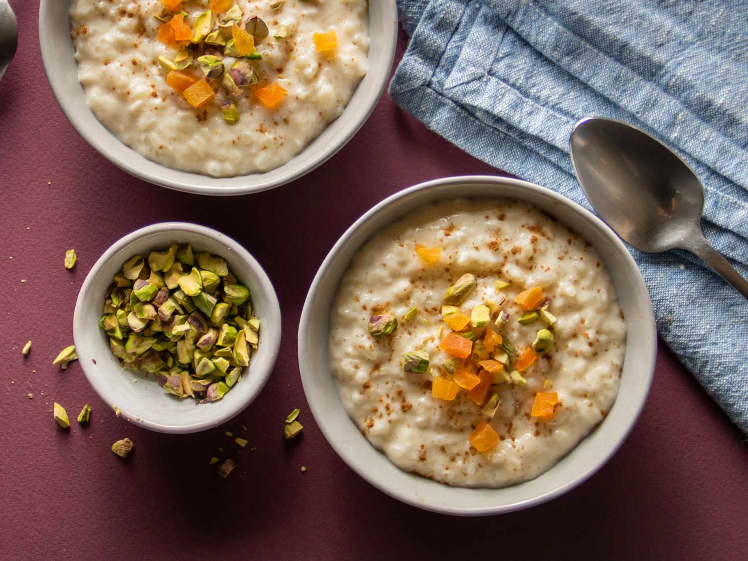 vanilla rice pudding in two bowls topped with dried apricots and pistachios