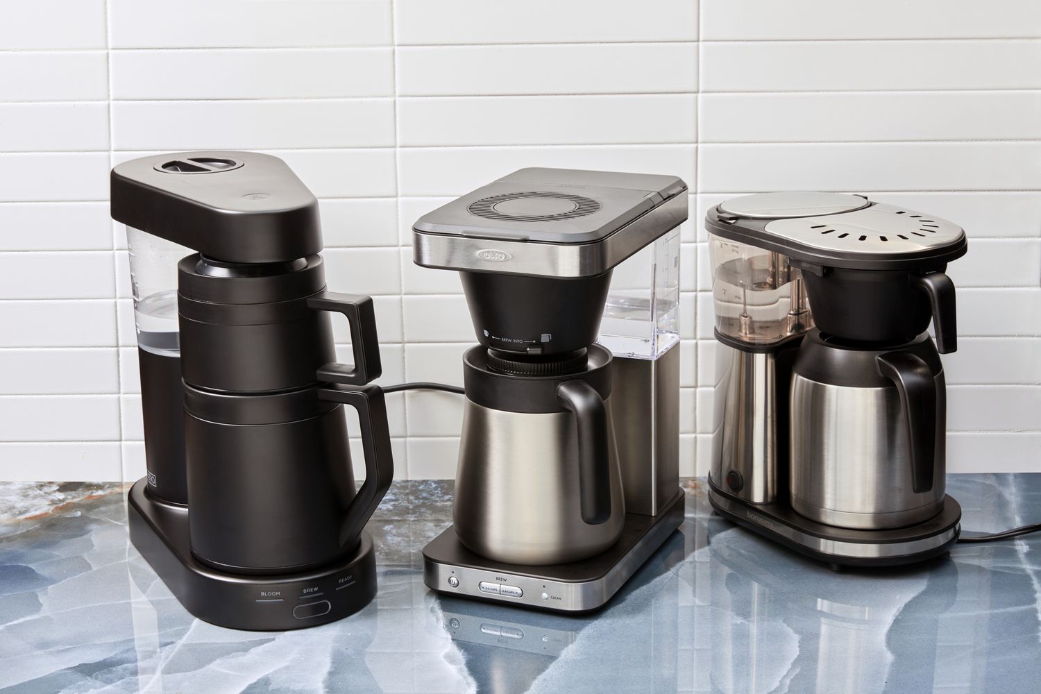 Three coffee makers on a blue kitchen countertop.