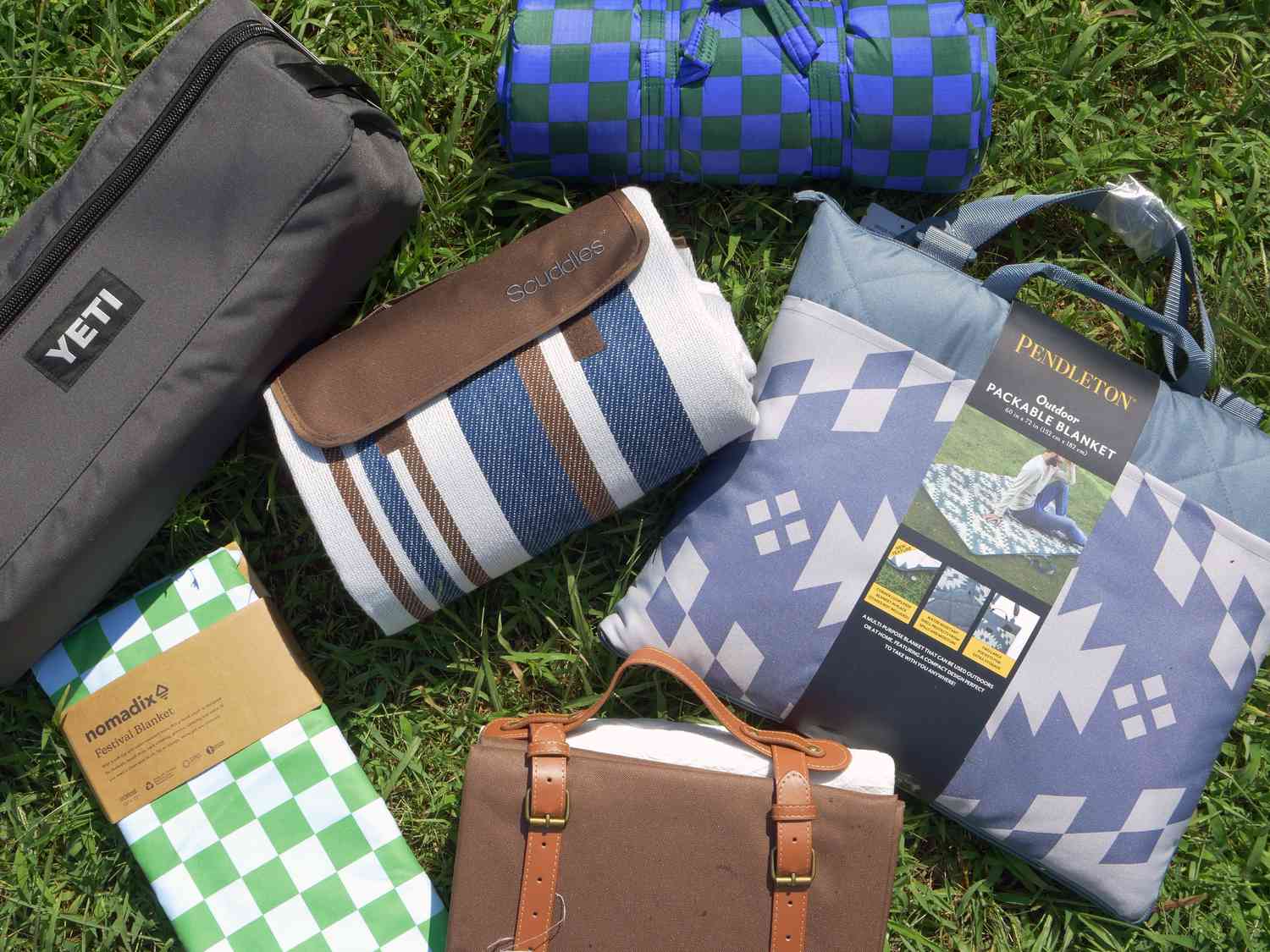 six picnic blankets folded up on grass