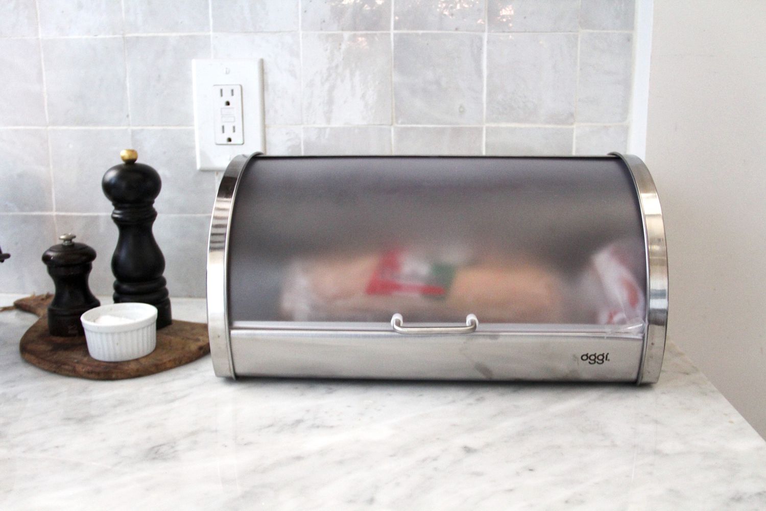 A bread box with a loaf of bread in it and its lid closed.