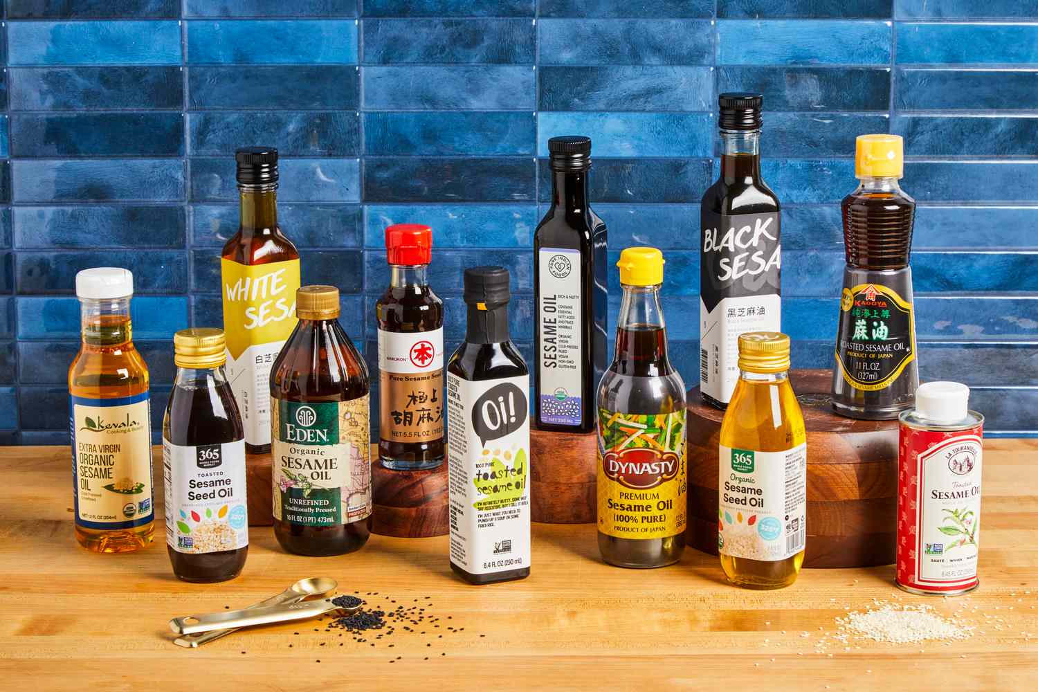 a variety of sesame oils on a wooden surface with a blue tile background