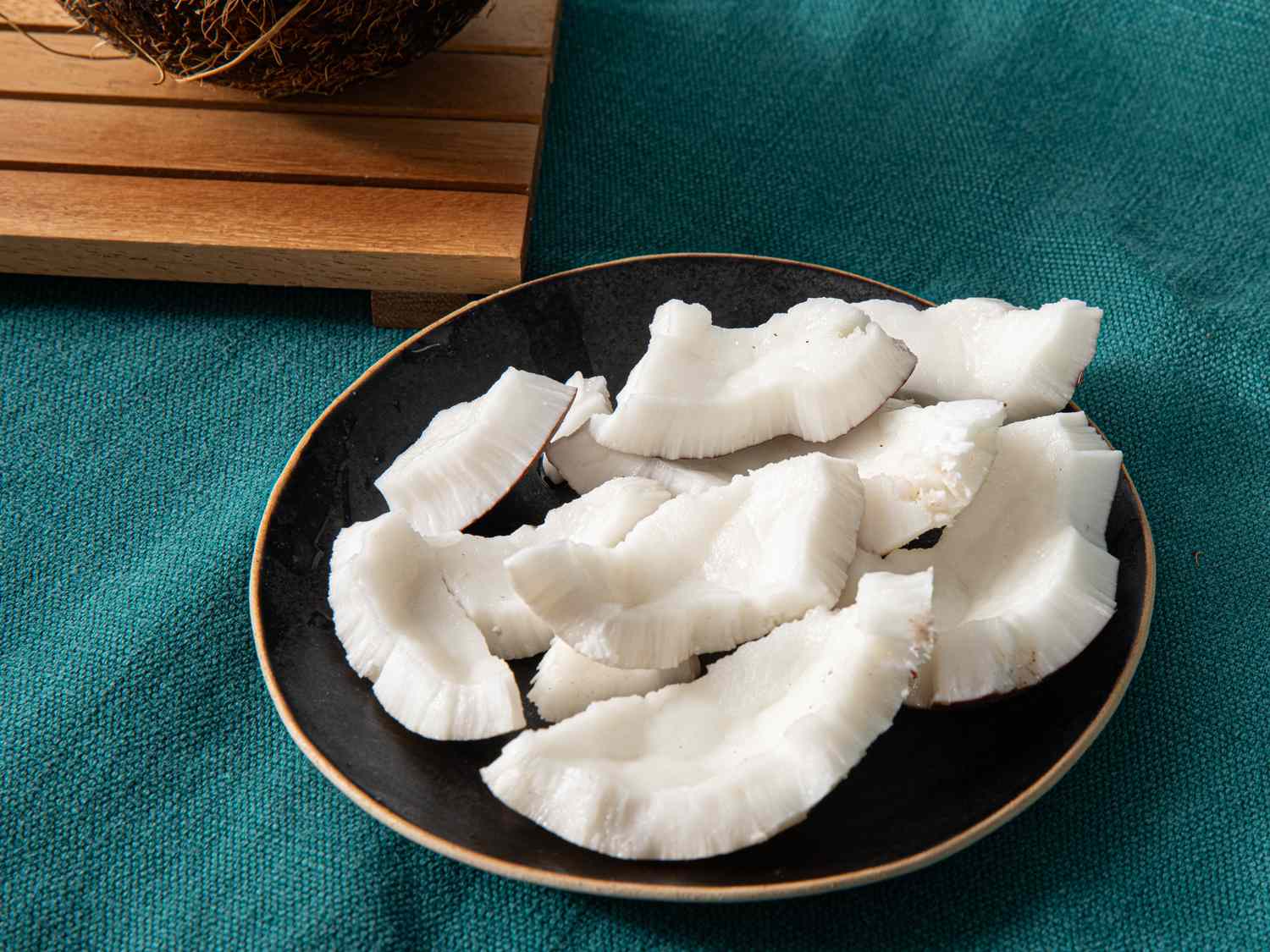 Overhead view of coconut pieces on a black plate