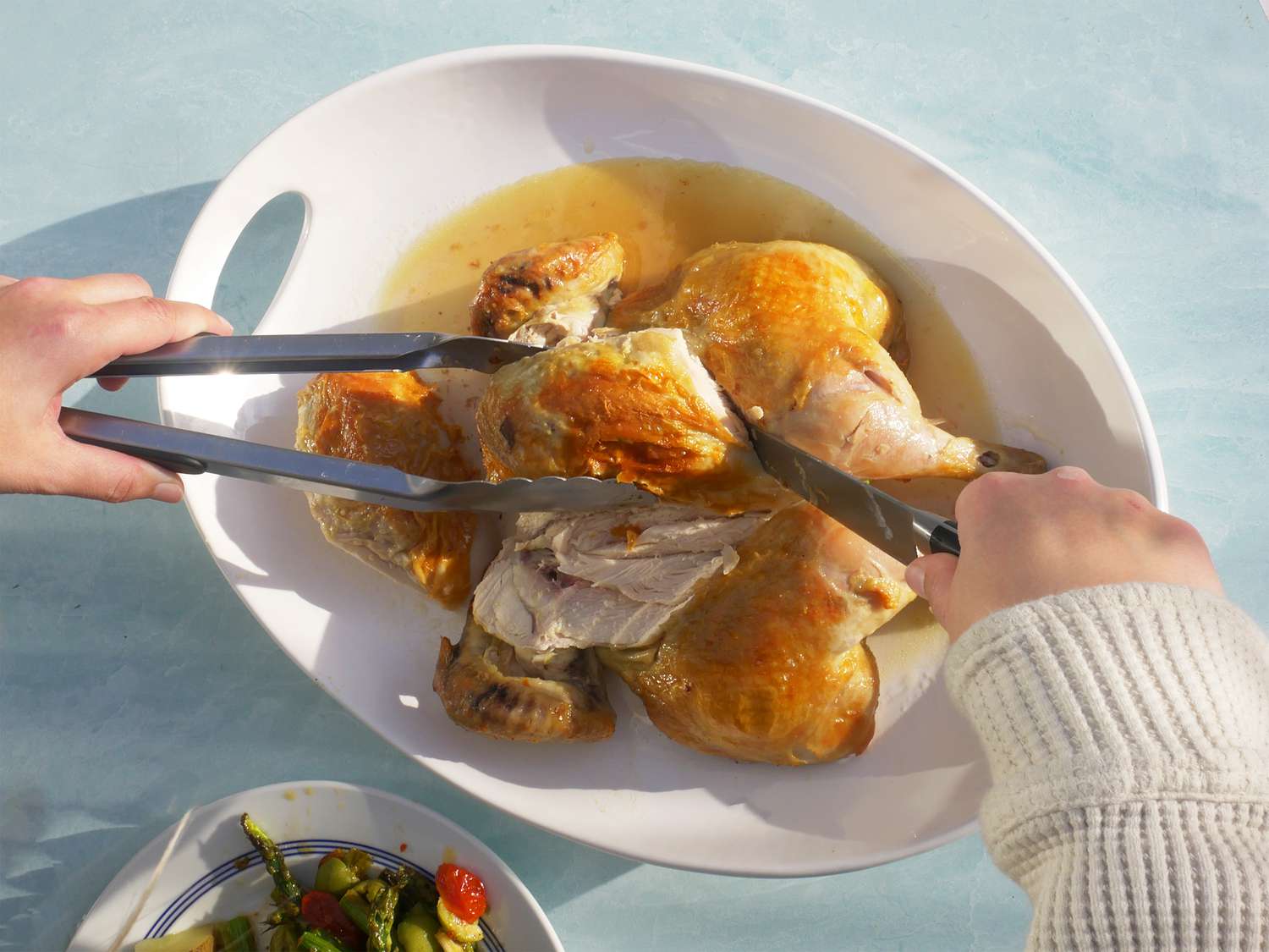 Carving a chicken on a white platter 