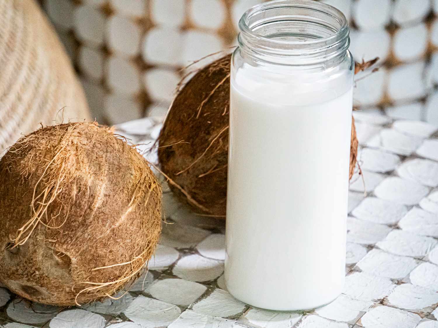 Side view of coconut milk surrounded by coconuts