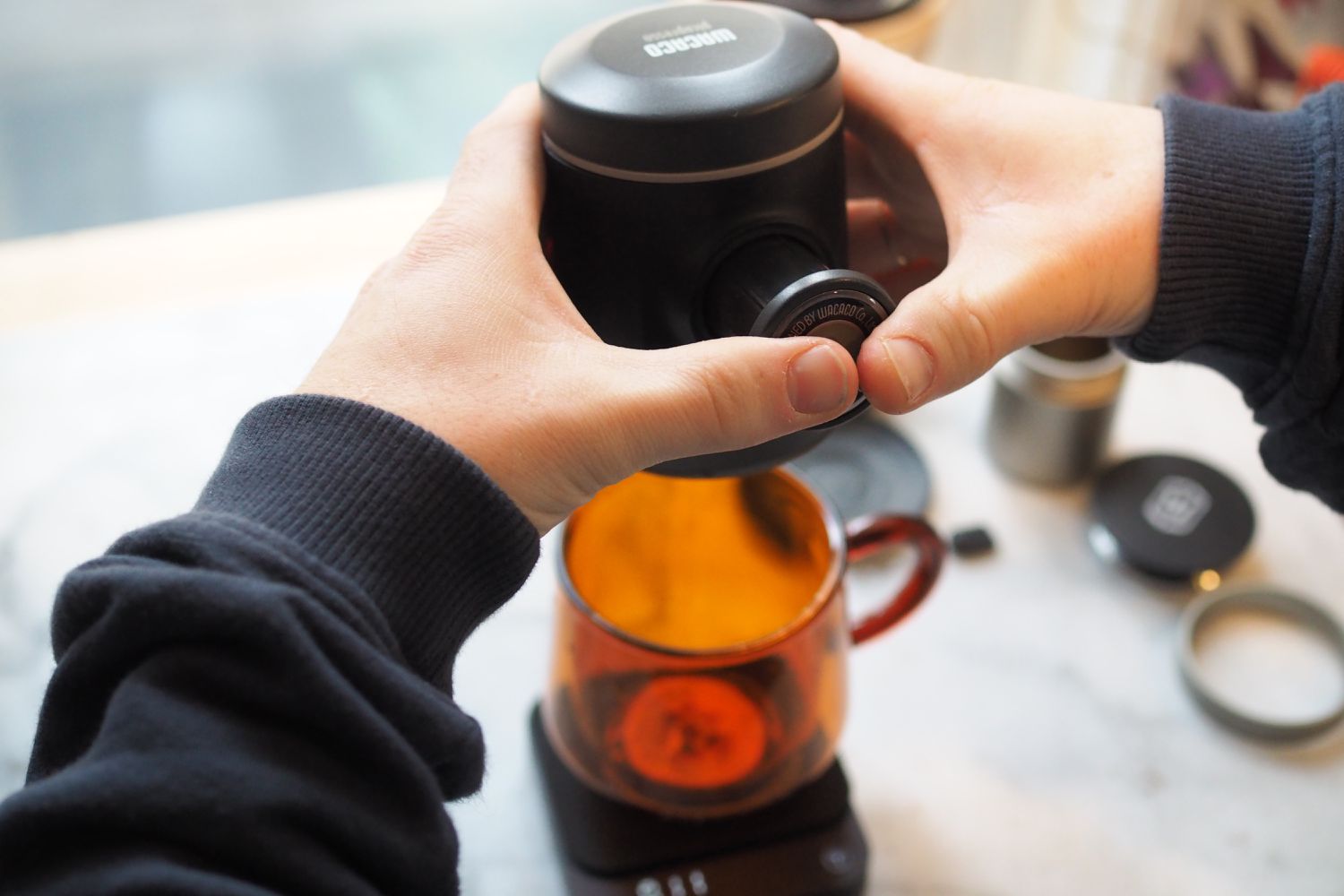 person adding topping to drink in orange glass mug