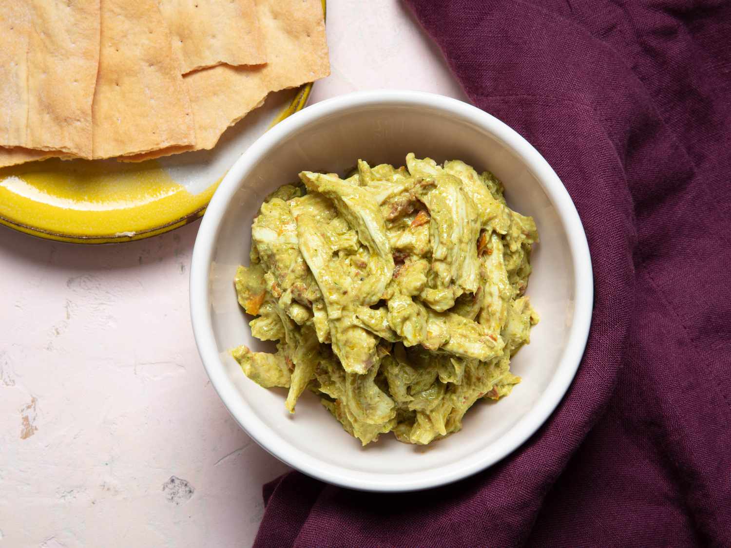 A bowl of pesto chicken salad with crackers on the side