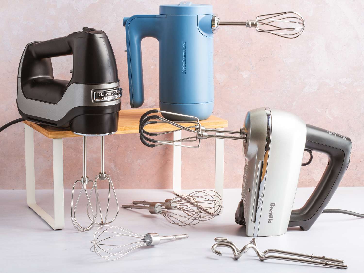 Three hand mixers on a white kitchen countertop.