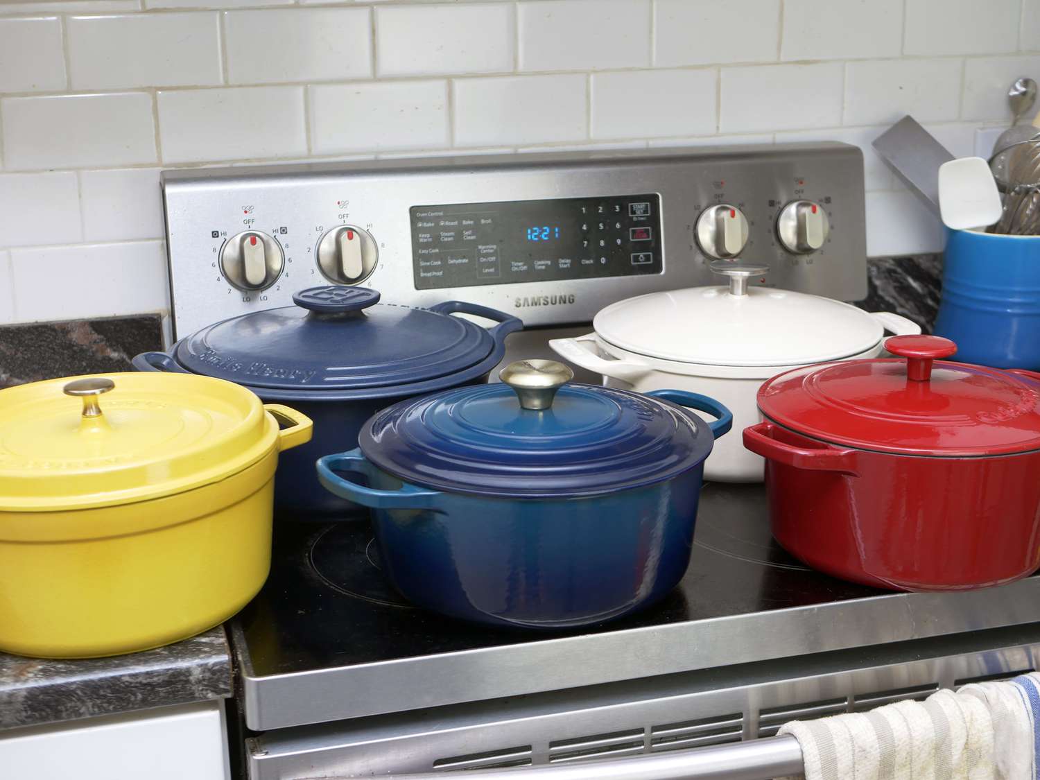 a variety of dutch ovens on a countertop and stove