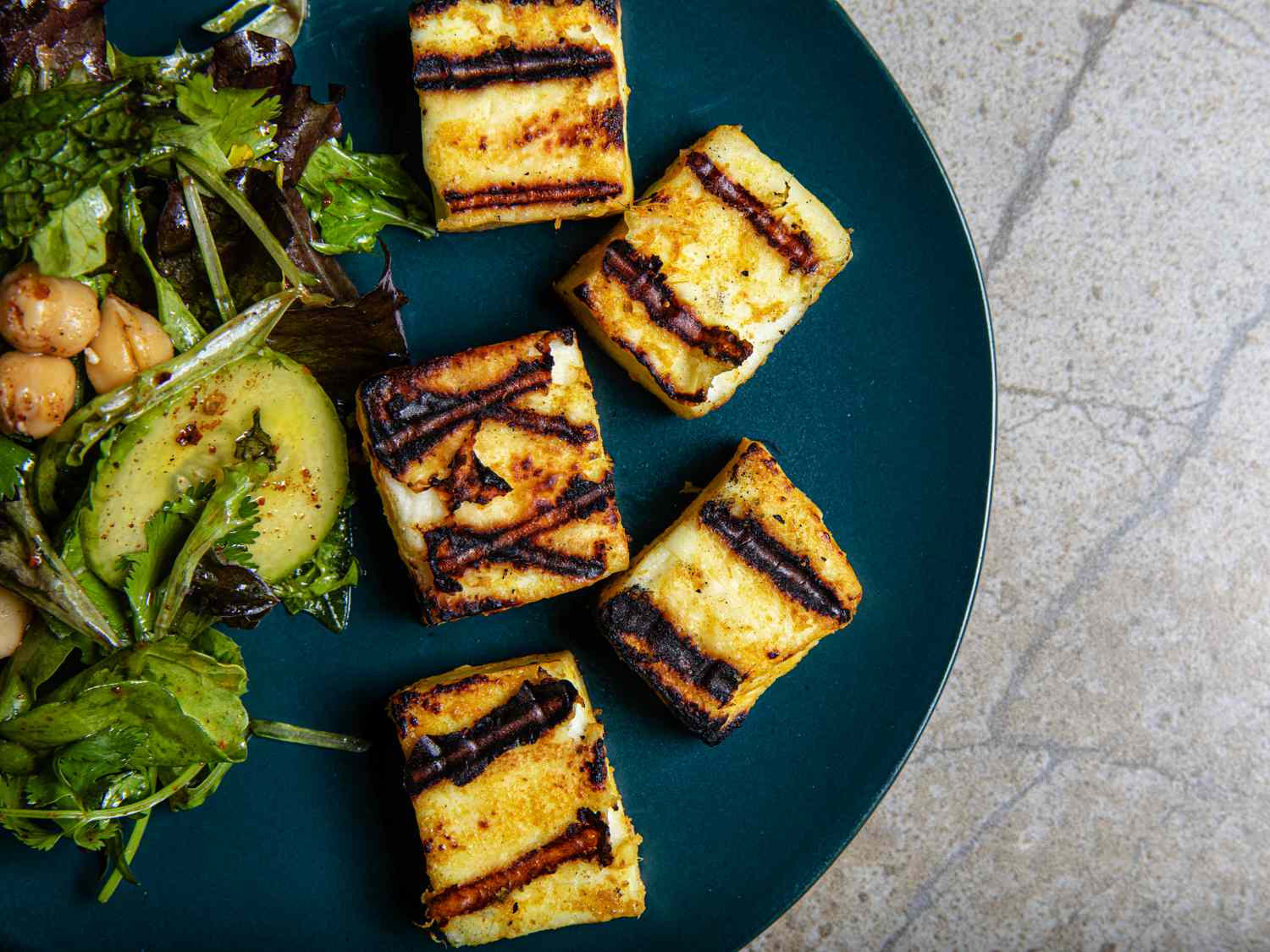 Cropped view of grilled paneer and chickpea salad on a blue plate