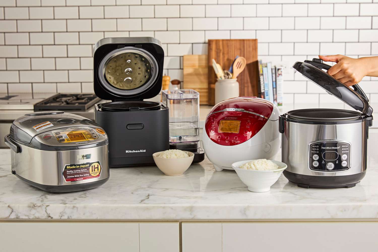 Four rice cookers on a kitchen countertop.