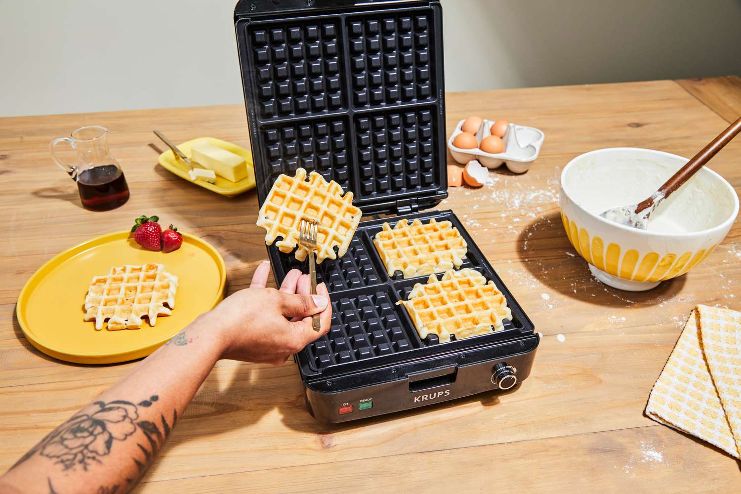 A Krups waffle maker, with cooked waffles on the plates.